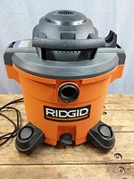 Front view of Ridgid WD12701 shop vac with no attachments visible, orange body and black top with handle and wheels.