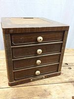 Front view of the wooden storage cabinet showing four drawers with wooden knobs and wood grain finish.