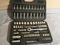 Full view of black plastic socket set case open, showing 74 pieces including 1/4 and 3/8 inch sockets, ratchets, and driver pieces all in place.