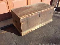 Closed wooden toolbox showing front latch and worn surface