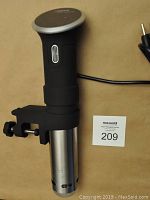 Anova immersion circulator attached to clamp laid on flat surface, power cord visible