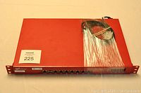 Wide angle view showing the full device including cables bundled and wrapped on top of the red metal rack-mount chassis.