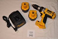 Full lot including DeWALT cordless drill, two 12V batteries, and charger seen arranged on white surface.