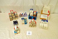 Overview of the collection of projector bulbs arranged on a light fabric surface, showing many boxes grouped by brand and type.