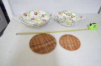 Two oval ceramic dishes with floral pattern in wire racks alongside two round rattan trivets on a white surface with measuring tape.