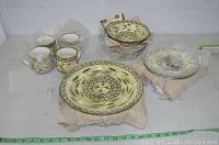 Full view of the 16 piece set arranged on a table, showing plates, bowls, and mugs with the detailed floral and olive branch pattern