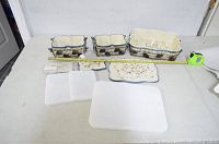 Overall view showing all components of the set including three ceramic dishes, matching lids, trivets, and metal racks.