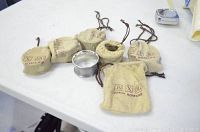 Six vintage John Somers pewter napkin rings each with a cloth pouch marked JS X MG and John Somers logos on a white table.