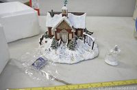 Snow-covered red schoolhouse ceramic figurine with small snowman accessory and original packaging.