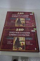 Two unopened boxes of 140 indoor Christmas lights with 16 functions, stacked on top of each other.