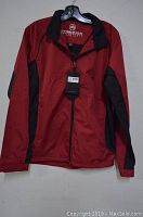 Front view of men's Stormtech jacket, showing red color with black side panels and sleeves, jacket hanging on hanger.