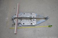 Full view of Sigma tile cutter on floor with measuring tape alongside.