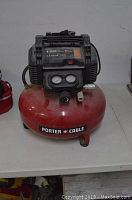 Front view of the red Porter Cable air compressor with visible brand logo and pressure gauges on top.