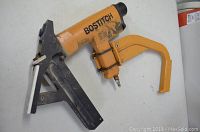 Photo of an orange Bostitch flooring nailer showing the body, handle, base plate, and pneumatic connection fitting.