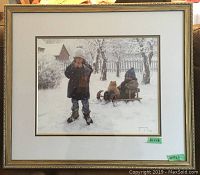 Framed winter scene print showing two children and a cat in snowy setting.