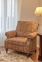 Side view of the upholstered chair showing fabric pattern, arm design, and wooden legs