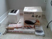 Photo showing Krups Meal Master sandwich maker box, white toaster, electric kettle, and shish kabob set box and skewer rack.