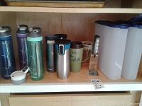 Image of multiple insulated water bottles including Contigo brand and plastic food storage containers with blue lids on shelves.