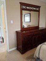 Full frontal view of dresser with attached mirror in bedroom setting