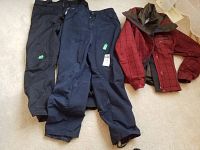 Three items: red Columbia ski jacket, black ski pants, navy ski pants on carpeted floor