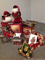 Full view of lot contents including plush figurines, porcelain Nativity scene box, candle holder, reindeer figure, tins, gift boxes, and decorative basket