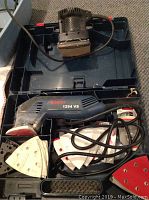 Bosch 1294 VS sander with sanding sheets, cords and carrying case interior.