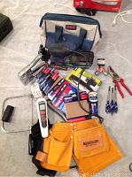 Full view of multiple hand tools, Bosch sander, tool pouch, staple gun, and accessories arranged on a surface.