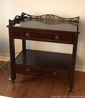 Front view of the wooden tea trolley showing two drawers, one large top drawer and two smaller ones below, lower shelf, and razors on wheels.