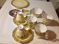 Photo showing multiple china pieces including Royal Standard teacups, saucers, a Shelley candy dish, and Royal Crown Derby small plate arrayed on a table