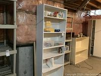 Full view of the white wooden shelving unit with various home improvement supplies on its shelves.
