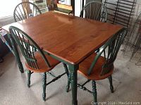 Dining table with 4 chairs arranged around it, showing table surface and chair design.