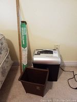 Overall lot photo showing shredder, meter stick, file frame box, and waste bin on floor.