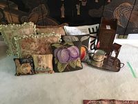 Eight decorative pillows with floral and animal designs, and a sectional view of the metal tray with wooden stand and cabinet in the background.