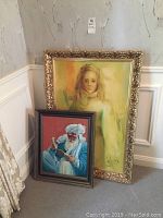 Large portrait painting of a girl framed ornately and smaller painting of a man in a turban reading.