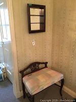 Wood bench with upholstered seat and carved wooden backrest and legs.