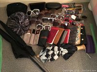 Photo showing sunglasses, umbrellas, clutch bags, glasses cases, and accessories arranged on the floor