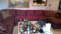 Front view of full burgundy sectional behind a coffee table with assorted bottles