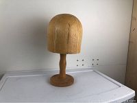 Photo showing the front view of the antique wooden hat mold on its pedestal base