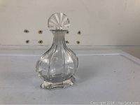 Full front view of Baccarat signed clear crystal perfume bottle with stopper on a plain surface.