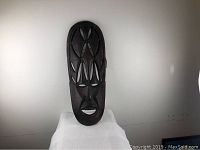 Front view of the large carved wooden mask showing intricate patterns and shapes.