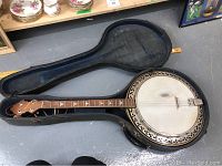 Full view of 5-string banjo inside open cloth-covered case with blue velvet lining