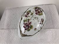 Top view of white blown milk glass egg with hand painted purple flowers, green leaves, gold accents, and handwritten text.