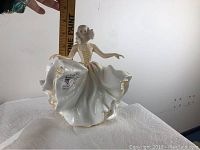 Porcelain figurine with measuring tape for scale showing height and details of dress and base mark.