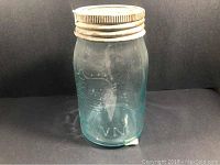 Side view of large blue glass sealer jar with metal lid showing embossing and general condition.
