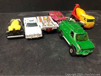 Lot of seven vintage diecast toy cars in a row on black surface.