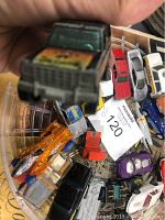 Close-up photo of black pickup truck with colorful painted hood held in hand, showing front detail and wear.