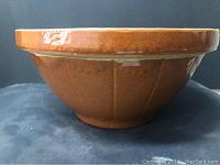 Side view of antique pottery mixing bowl showing brown glaze and subtle vertical ridges