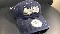 Navy blue baseball cap with worn holes and distressed fabric showing 'Maple Leafs' embroidery on front.