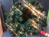 Full view of the green wreath illuminated by warm white LED lights.