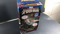 Box front showing the Marvel Ultimate Spider-Man LED light show product with colorful light effect graphics and branding.